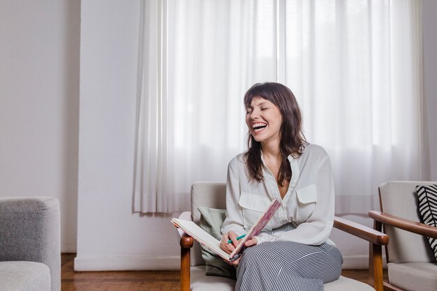 Lachende Frau auf Stuhl mit Buch