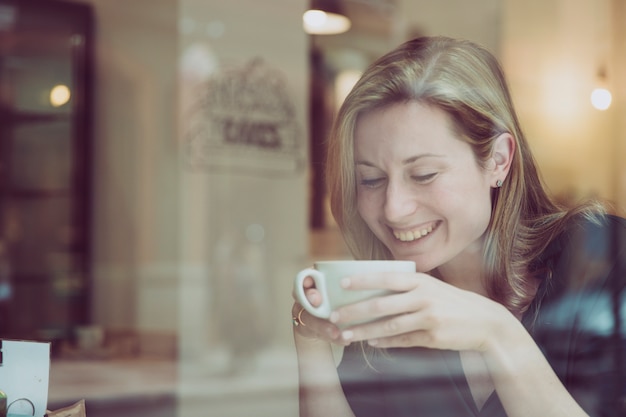 Kostenloses Foto lachende frau, die im café trinkt