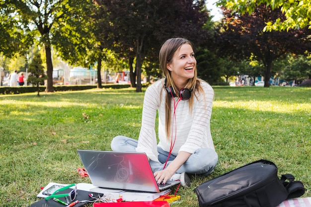 Lachende Frau, die im Park studiert