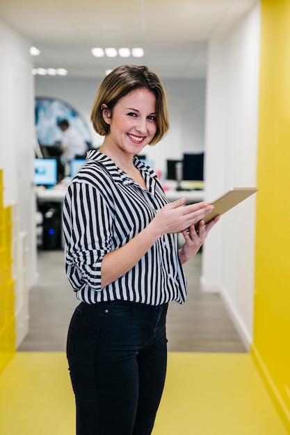 Lachende Frau, die Tablette im Büro hält