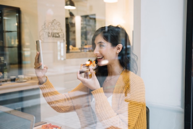 Kostenloses Foto lachende frau mit dem essen, das selfie nimmt