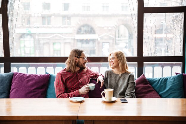 Lachende Frau und bärtige Mannfreunde, die im Café sitzen