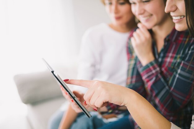 Lachende Frauen, die zusammen Tablette verwenden