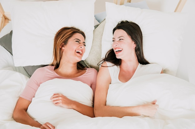 Lachende Frauen im Bett liegend