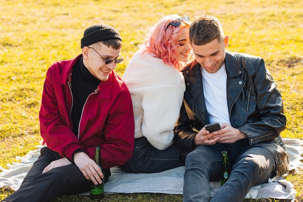 Lachende Freunde, die Spaß haben, zusammen auf Gras zu sitzen