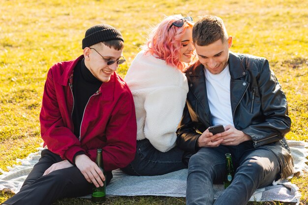 Lachende Freunde, die Spaß haben, zusammen auf Gras zu sitzen