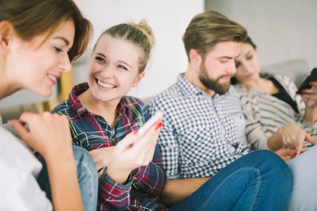 Kostenloses Foto lachende freunde mit gadgets auf sofa