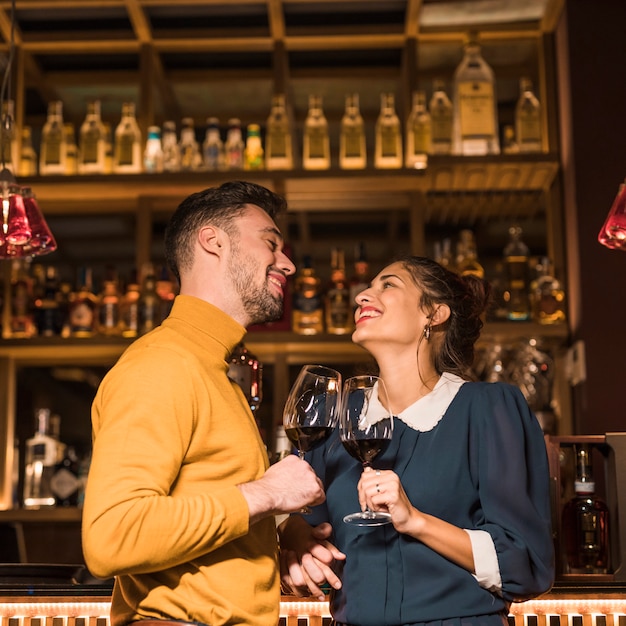 Kostenloses Foto lachende klirrende gläser des mannes wein mit lächelnder frau