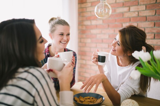 Lachende Mädchen, die Tee trinken und sprechen