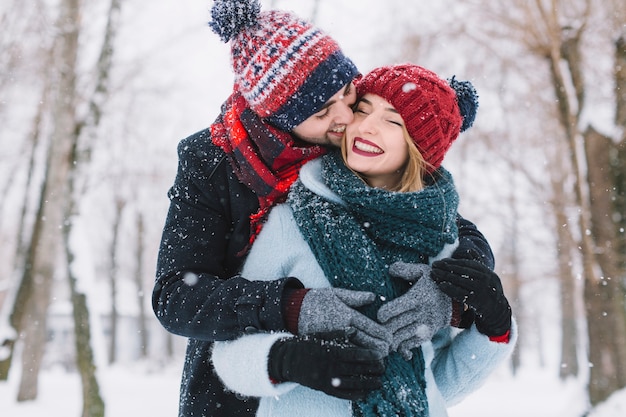 Lachende Paare in den Schneefällen küssen
