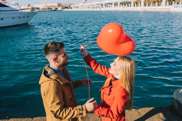 Kostenloses Foto lachende paare mit rotem herzballon