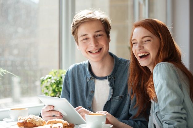 Lachende Studenten, die im Café sitzen