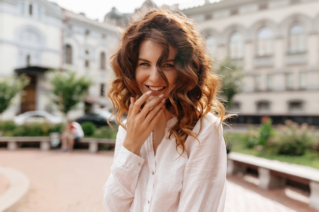 Lachende süße Frau mit Locken haben eine tolle Zeit beim Wandern im Freien in der Stadt an einem guten sonnigen Tag