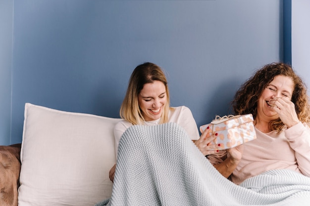 Lachende Tochter, die der Mutter Geschenk gibt