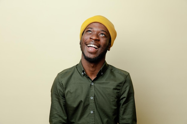 Lachender junger afrikanisch-amerikanischer Mann mit Hut, der ein grünes Hemd auf weißem Hintergrund trägt