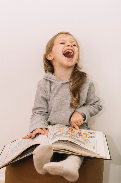 Lachendes Mädchenlesebuch auf Pouf