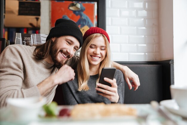 Lachendes Paar, das Telefon im Café betrachtet