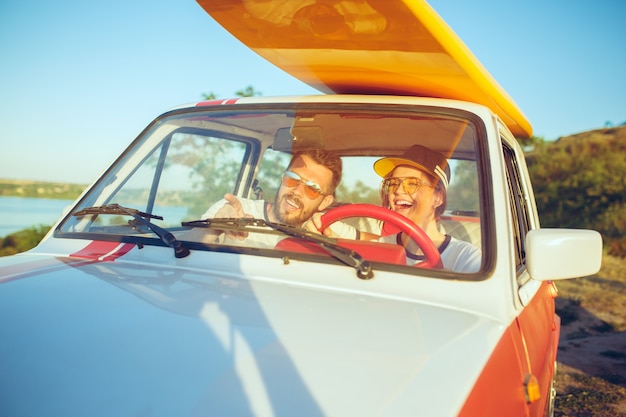 Lachendes romantisches Paar, das auf einem Roadtrip im Auto sitzt.