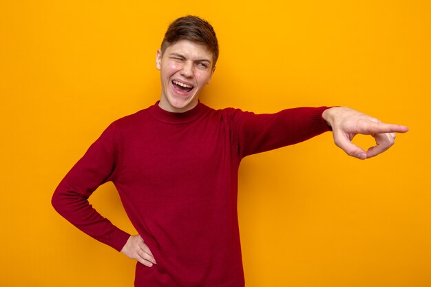 Lachpunkte an der Seite junger gutaussehender Kerl mit rotem Pullover