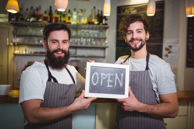 Lächelnd Kellner mit offenen Schild im Café stehen