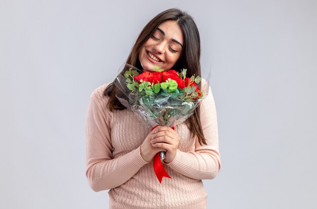 Lächelnd mit geschlossenen Augen kippendes junges Mädchen am Valentinstag mit Blumenstrauß isoliert auf weißem Hintergrund