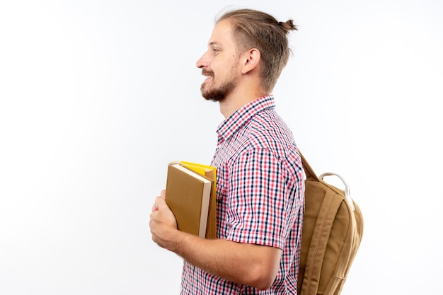 Lächelnd stehend in der Profilansicht junger Kerl Student mit Rucksack mit Büchern