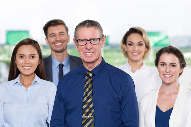 Lächelnde ältere Business Leader mit dem Team Standing