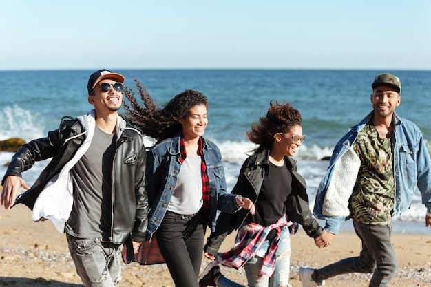 Lächelnde afrikanische Freunde, die draußen am Strand gehen.