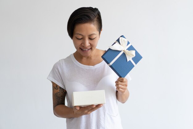 Lächelnde Asiatin, die offene Geschenkbox untersucht