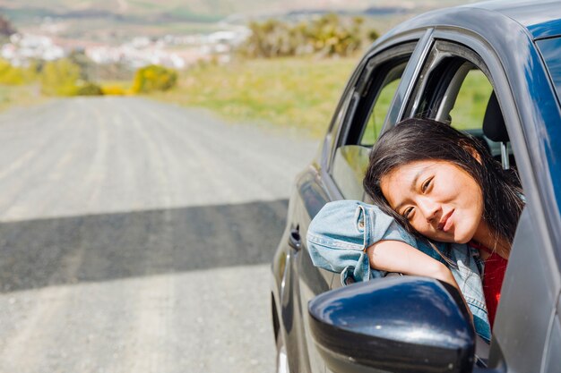 Lächelnde asiatische Frau, die aus Auto heraus schaut