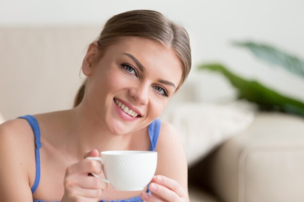 Lächelnde attraktive Frau der Junge, die den Kaffee betrachtet Kamera genießt