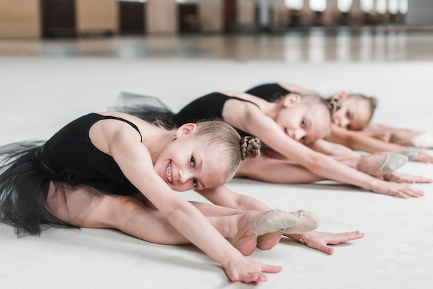 Kostenloses Foto lächelnde ballerinamädchen, die auf tanzboden aufwerfen