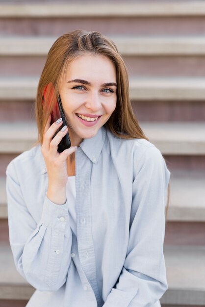 Lächelnde blonde Frau, die am Telefon spricht