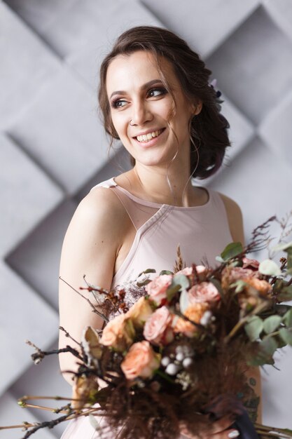 Lächelnde Braut mit nahem Porträt des Blumenstraußes im Studio