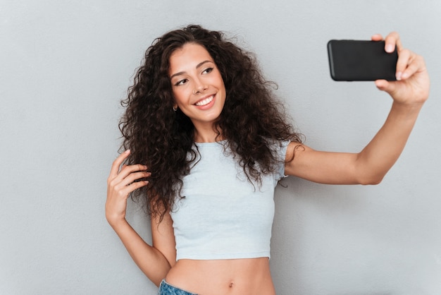 Lächelnde brünette Frau, die selfie am Telefon macht