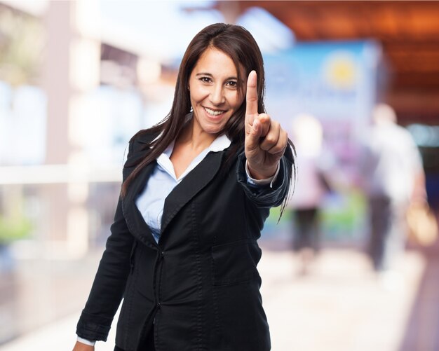 Lächelnde elegante Frau mit einem erhobenen Zeigefinger