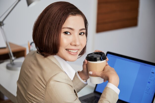 Lächelnde ethnische Geschäftsfrau mit Kaffee