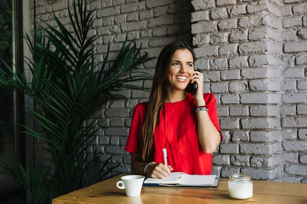 Kostenloses Foto lächelnde frau, die auf mobiltelefon in cafã? spricht