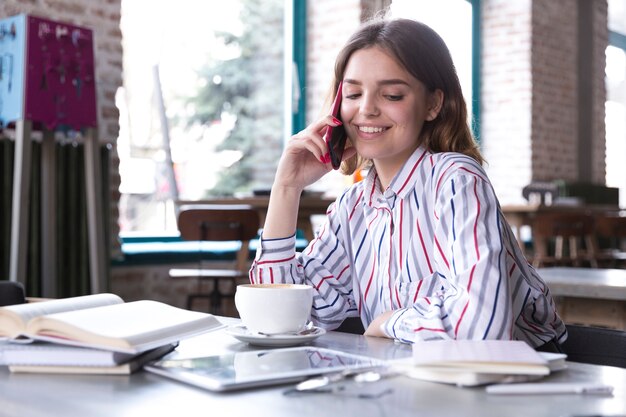 Lächelnde Frau, die auf Smartphone spricht