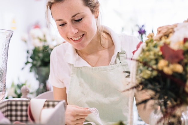 Lächelnde Frau, die Bänder für Blumenstrauß wählt