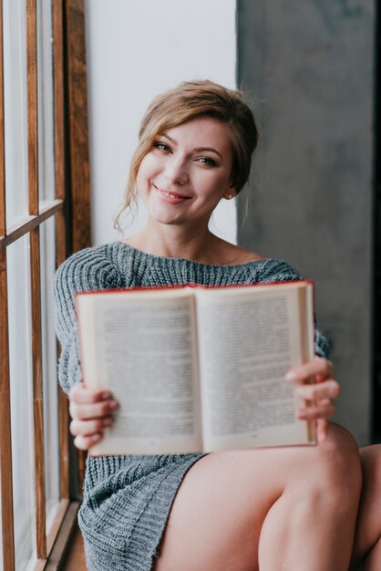 Lächelnde Frau, die Buch zeigt