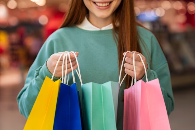 Lächelnde Frau, die bunte Papiertüten hält