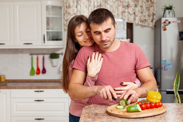 Kostenloses Foto lächelnde frau, die das mannkochen umfasst