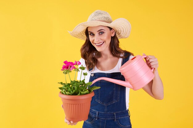 Lächelnde Frau, die die Blume in der Studioaufnahme gießt