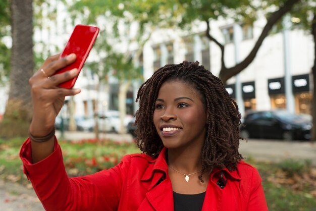 Lächelnde Frau, die draußen selfie mit Smartphone nimmt