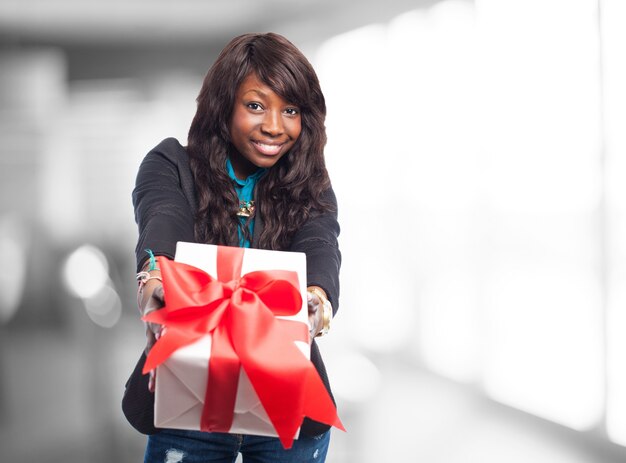 Lächelnde Frau, die ein Geschenk mit rotem Band halten