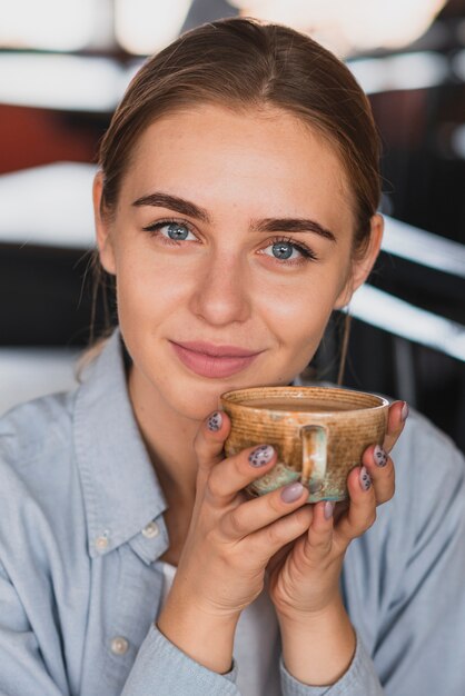 Lächelnde Frau, die eine Schale nah an ihrem Gesicht hält