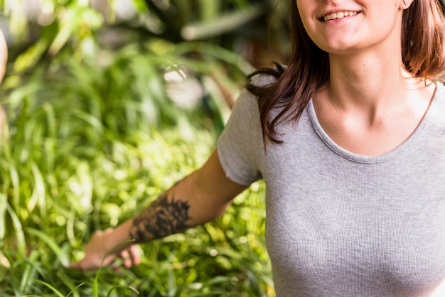 Kostenloses Foto lächelnde frau, die grüne blätter von anlagen hält