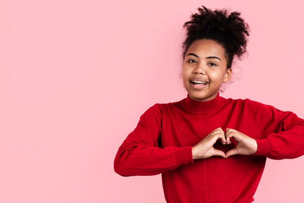 Lächelnde Frau, die heart-shaped Hände bildet