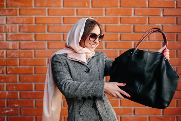 Lächelnde Frau, die ihre Handtasche zu bewundern